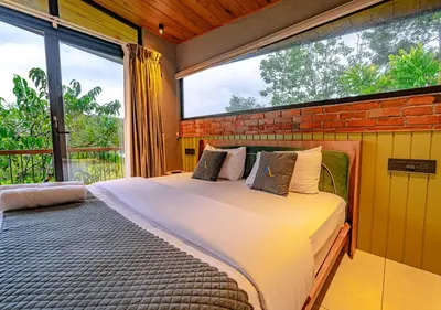 a bedroom with a bed and a large window at Alaya Boutique Villa with Dam View by VOYE HOMES in Vythiri