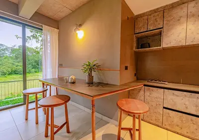 a kitchen with a wooden table and some stools at Alaya Boutique Villa with Dam View by VOYE HOMES in Vythiri