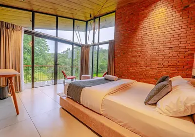 a bedroom with a large bed and a brick wall at Alaya Boutique Villa with Dam View by VOYE HOMES in Vythiri