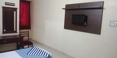 a room with a bed and a tv on a wall at Mahe Residency in Mahe