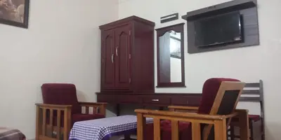 a dining room with two chairs and a dresser and a tv at Mahe Residency in Mahe