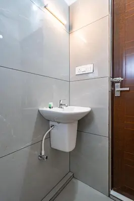 a white bathroom with a sink and a shower at D Nest Inn in Trichūr