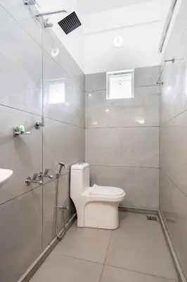 a white bathroom with a toilet and a shower at D Nest Inn in Trichūr