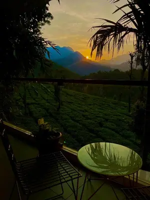 a table and a chair on a balcony with a view at Hayashi Resort in Meppādi