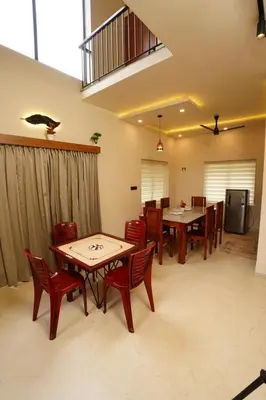 a dining room with wooden tables and red chairs at LA VILLA VYTHIRI Resort in Vythiri