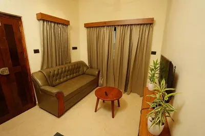 a living room with a couch and a table at LA VILLA VYTHIRI Resort in Vythiri