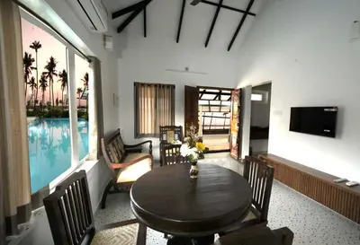a living room with a table and chairs and a pool at Dhruv Heritage Lake Resort Cherai in Cochin