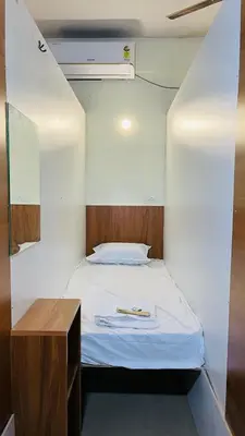 a small bedroom with a bed and a table at Tokyo Dorms in Kozhikode