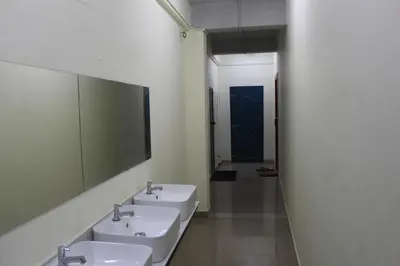 a bathroom with three sinks and a blue door at Tokyo Dorms in Kozhikode