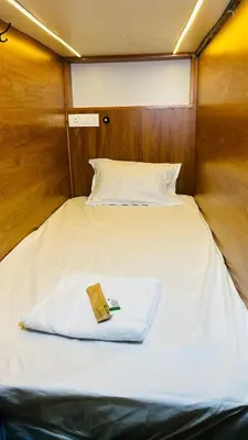a bed in a small room with a book on it at Tokyo Dorms in Kozhikode