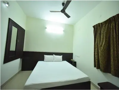 a bedroom with a white bed and a ceiling fan at PRM Aruna Lodge in Erode