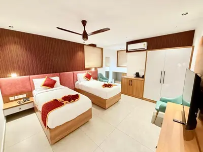 a hotel room with two beds and a refrigerator at Denz Paradise in Kelakam