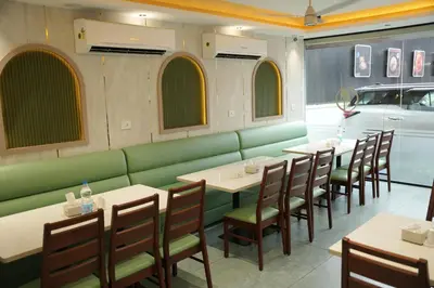 a restaurant with a green bench and tables and chairs at Denz Paradise in Kelakam