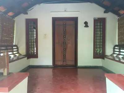 an empty room with a wooden door and two windows at Utthara Tharavadu in Irinjālakuda