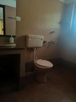 a bathroom with a toilet and a sink and a mirror at Utthara Tharavadu in Irinjālakuda