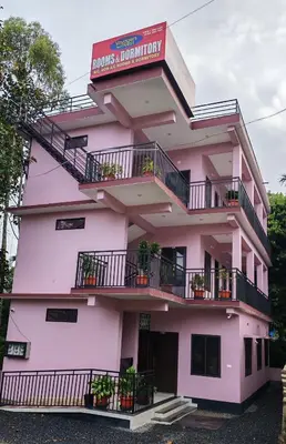 a pink building with balconies and a sign on it at Voyagers Nest Wayanad in Ambalavayal