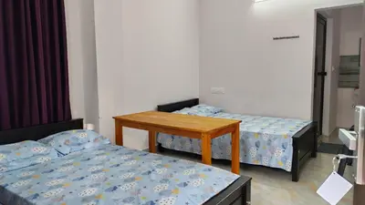 a room with two beds and a wooden table at Voyagers Nest Wayanad in Ambalavayal