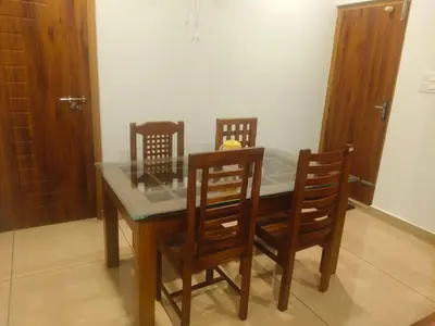 a dining room table with four chairs and a glass top at Wayanad Home stay in Kaniyāmbetta