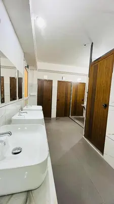 a large bathroom with three sinks and two toilets at LF Hotels in Kozhikode