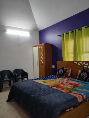 a bedroom with a bed with a blue comforter and chairs at HILL view ooty HOME Stay in Coimbatore