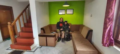 two people sitting on a couch in a room with a green wall at HILL view ooty HOME Stay in Coimbatore
