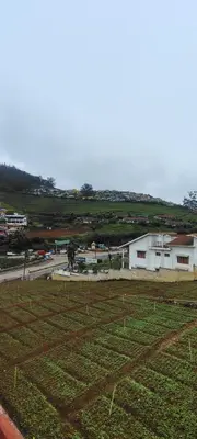 a field of grass next to a white building at HILL view ooty HOME Stay in Coimbatore