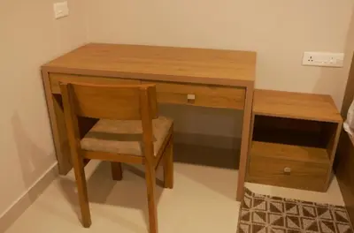 a wooden desk with a chair next to a wooden cabinet at LAVENDER AiRPORT SUiTE in Nedumbassery