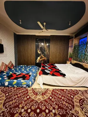a bedroom with two beds and a painting on the wall at Mysore City Vibe By A1k in Mysore