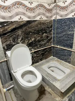 a bathroom with a white toilet and a sink at Mysore City Vibe By A1k in Mysore