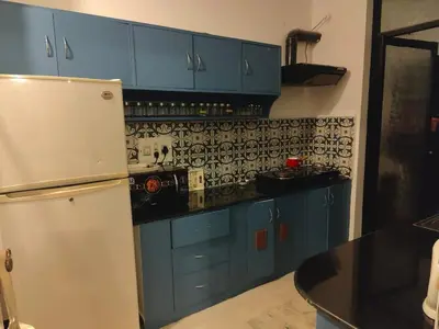 a kitchen with blue cabinets and a white refrigerator at 3 BHK Flat for rent at Mysuru in Mysore