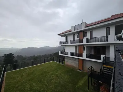 a balcony of a building with a green lawn at Indhraprashtham in Aruvankadu