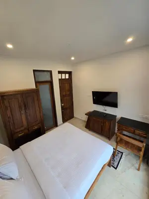 a bedroom with a bed and a flat screen tv at Indhraprashtham in Aruvankadu