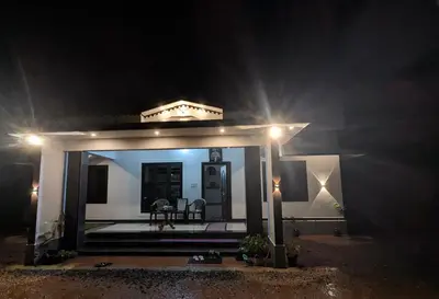 a small white house at night with lights at Gods Gift Homestay James Inn in Kozhikode