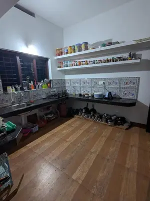 a kitchen with a wooden floor and shelves at Gods Gift Homestay James Inn in Kozhikode