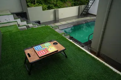 a table sitting on the grass next to a swimming pool at LA VILLA Resort in Vythiri