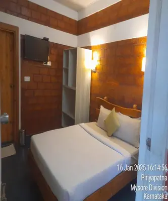 a bedroom with a bed and a tv on a wall at Atithi Devo Resort Coorg by LexStays in Kushālnagar