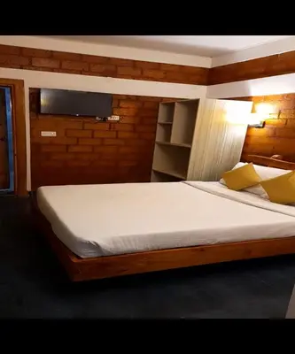 a bedroom with a large bed with white sheets and yellow pillows at Atithi Devo Resort Coorg by LexStays in Kushālnagar