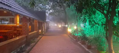 a street at night with a brick sidewalk and trees at Atithi Devo Resort Coorg by LexStays in Kushālnagar