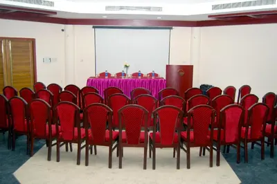 a conference room with a table and red chairs at Hotel KPM Tripenta in Palakkad
