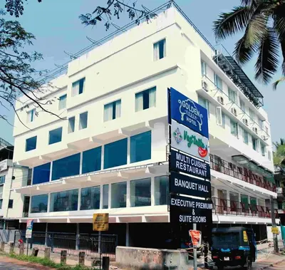 a white building with a sign in front of it at Hotel Golden Couch in Badagara