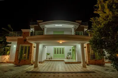 a large white house with a green door at night at GEE DE Homes in Kizhake Chālakudi