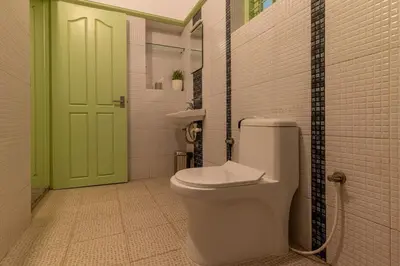a bathroom with a toilet and a green door at GEE DE Homes in Kizhake Chālakudi