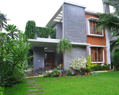 a house with a green yard in front of it at Midtown Meadow in Kozhikode