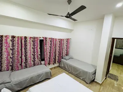 a living room with two beds and a ceiling fan at LUXE Premium Service Appartment in Mysore