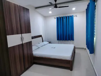a small bedroom with a bed and a blue curtain at Ambadi Blueberry in Guruvāyūr