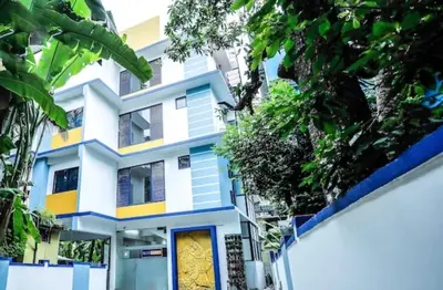 a white and blue building with a yellow door at Ambadi Blueberry in Guruvāyūr