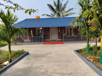 a building with a blue roof and palm trees at Mountain View Stay in Kushālnagar
