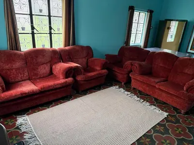 a living room with red couches and a rug at JMS Holiday homes in Coonoor
