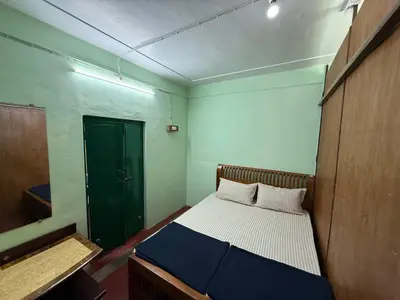 a small room with a bed and a green door at JMS Holiday homes in Coonoor