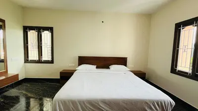 a bedroom with a large bed and two windows at Away From Home - 9 - HomeStay, Entire 2 BHK Villa in Ooty